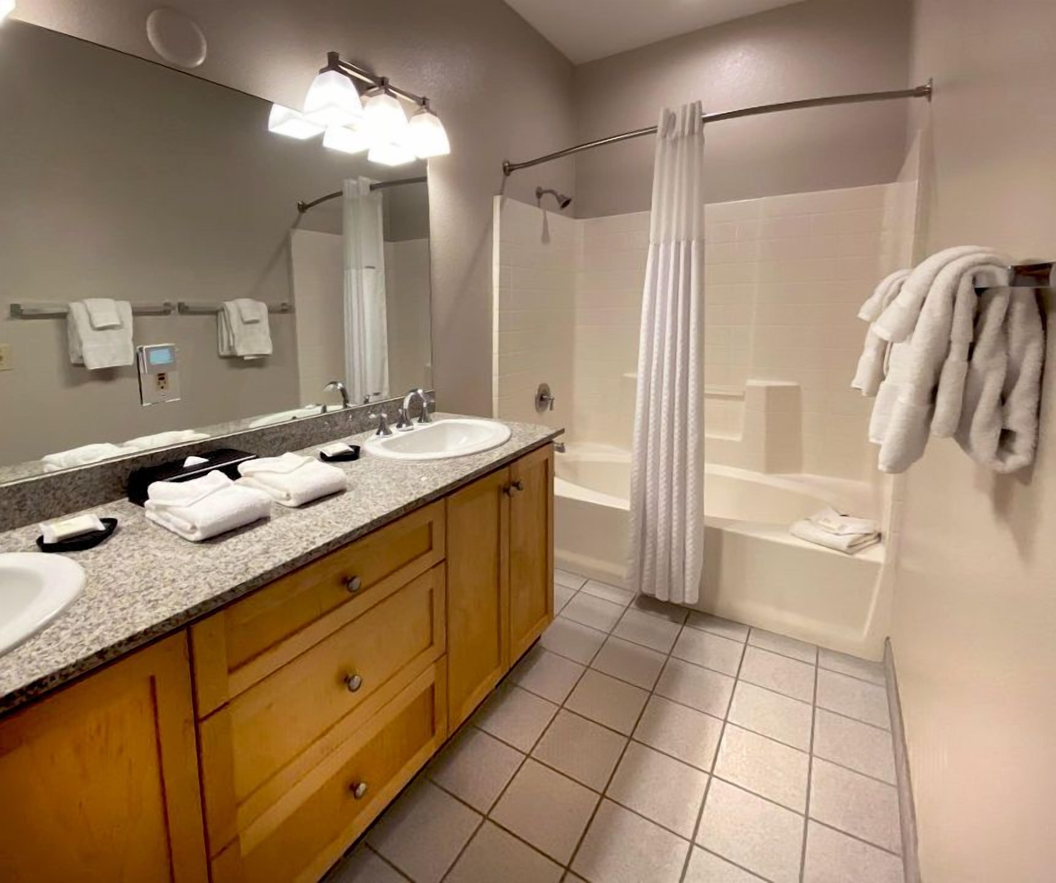 Une salle de bain moderne avec deux lavabos, un grand miroir et un espace douche.