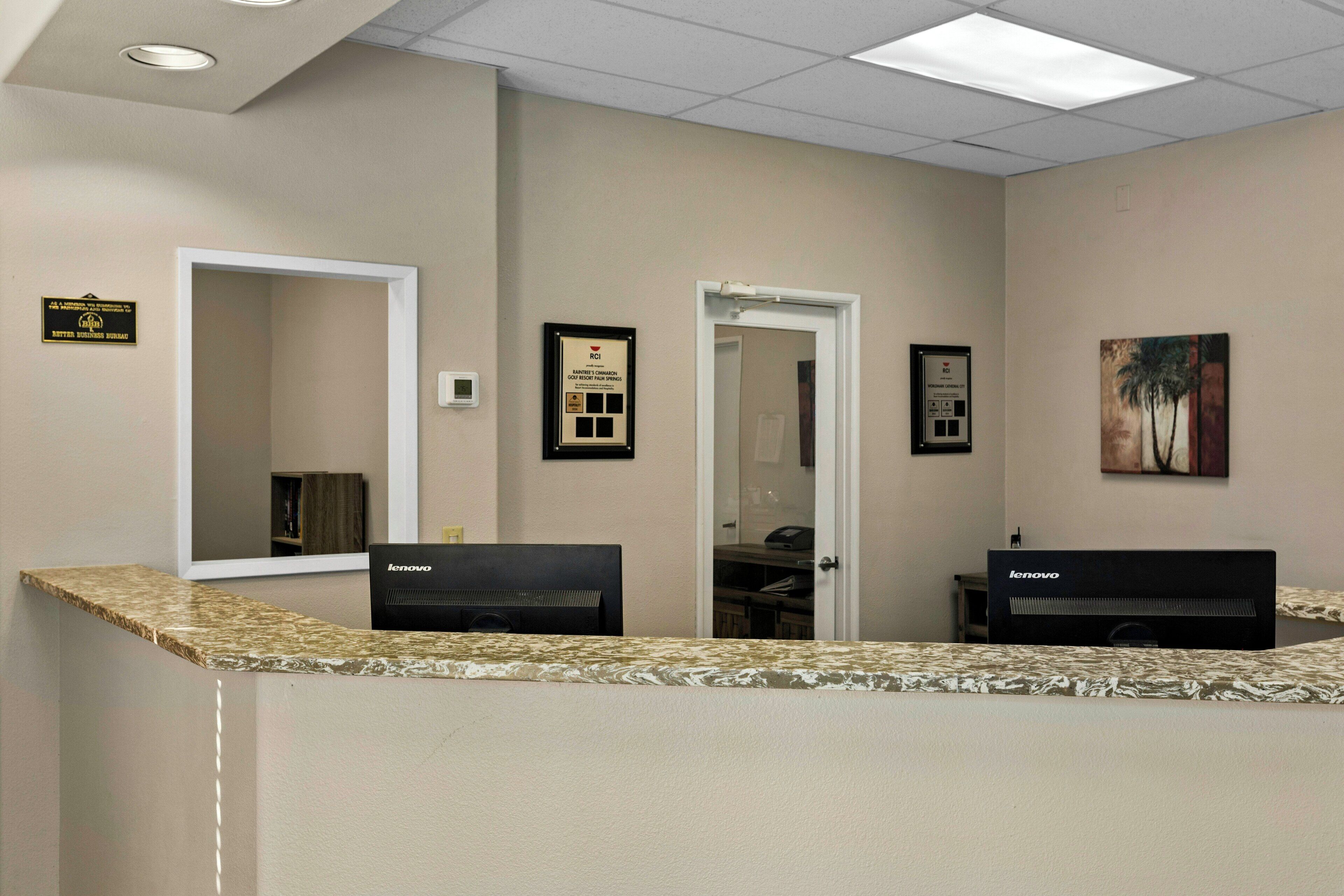 A reception area with two desks, a large mirror, and framed awards on the wall.