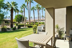 An outdoor patio with a table and chairs, surrounded by palm trees and a view of a mountain range. - Worldmark Cathedral City (Cathedral City)