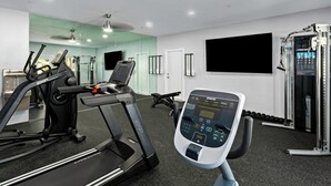 Une salle de sport moderne équipée de tapis de course, de vélos d’exercice et d’appareils de musculation.