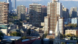 A cityscape with modern buildings, a prominent church, and snow-capped mountains in the background. - Alto San Isidro (Santiago)