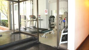 Een sportschool met fitnessapparatuur, een rookvrij bord en een glazen toegangsdeur.