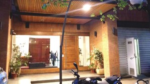 Ein Gebäudeeingang mit Holzfassade, Pflanzkübeln und einem abgestellten Motorrad.