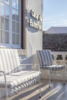 A balcony with a sofa and chairs, a window, and a sign reading "Casa da Estefã."