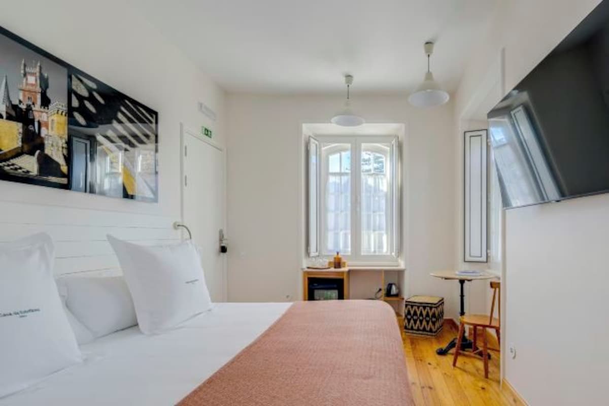 Una habitación de hotel con cama, un ventanal grande, un escritorio y una silla.