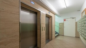 Ein Aufzugsbereich mit drei Aufzügen, einem Brandmelder und einem Stauraum mit Schubladen.