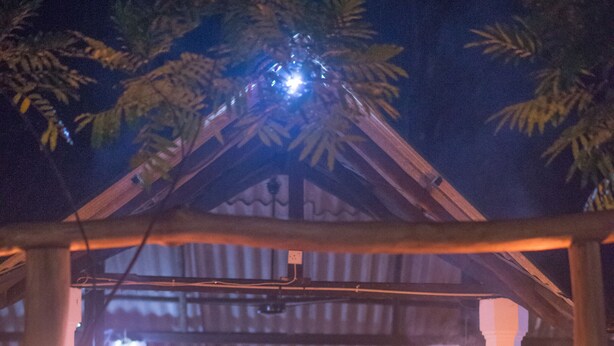 A wooden pergola with a table and chairs under a canopy, lit by candles. - Apsaras Resort Sigiriya (Sigiriya)