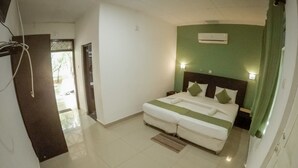 A bedroom with a bed, bedside tables, an air conditioner, and a view of the outside. - Apsaras Resort Sigiriya (Sigiriya)