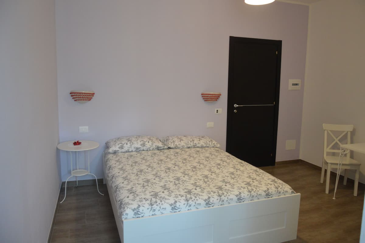 A small, neatly arranged bedroom with a bed, a small table, and a chair.