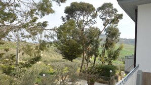 Varanda com vista para um jardim bem cuidado e colinas ao longe.