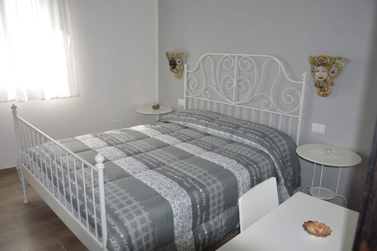 A neatly arranged bedroom with a bed, bedside tables, and decorative wall art.