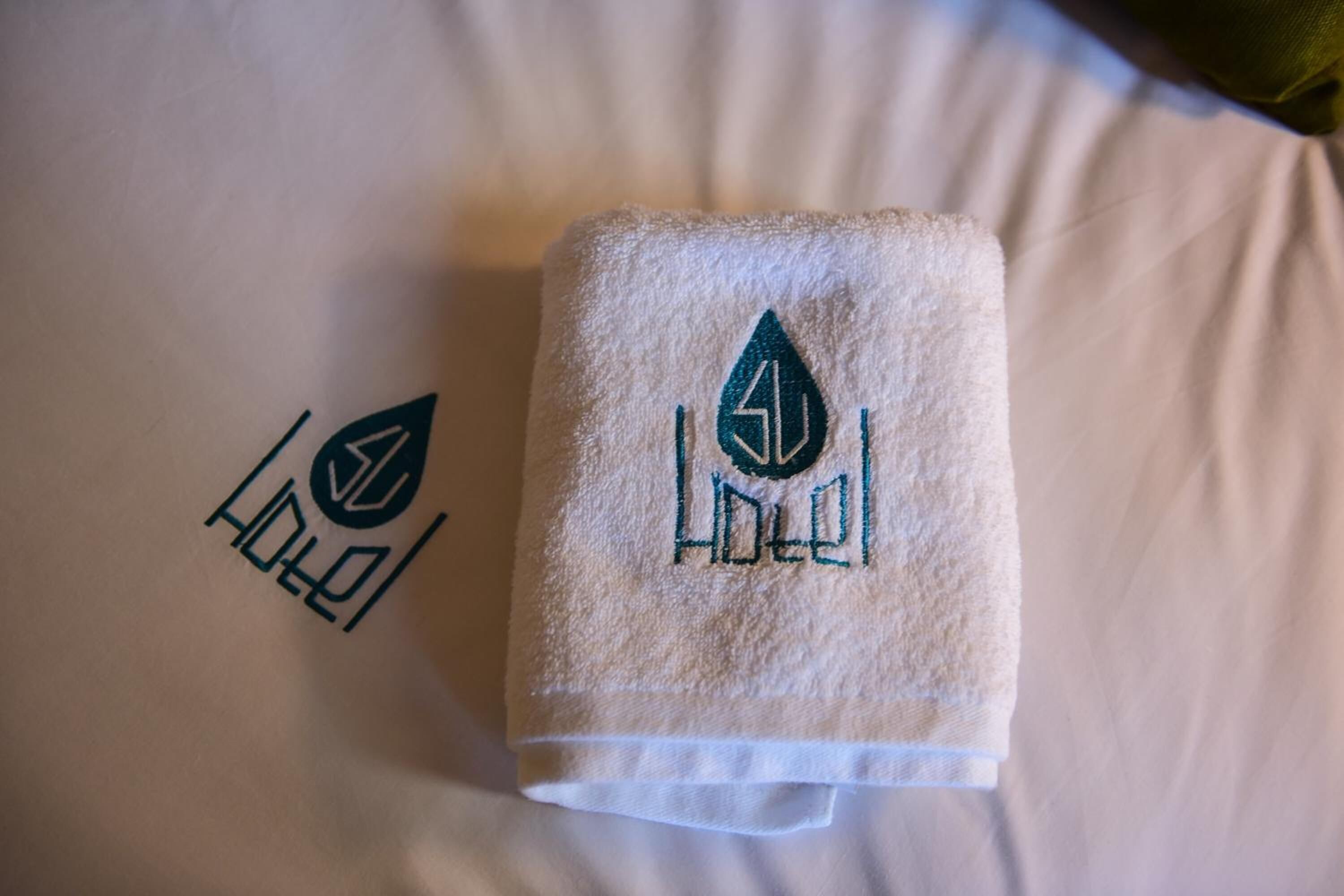 Une serviette soigneusement pliée, ornée d’un logo, posée sur un lit.
