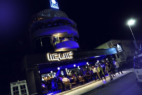 Un edificio con un letrero que dice 'LIQUID', un letrero que dice 'SU HOTEL' y una estructura en forma de cúpula con luces.