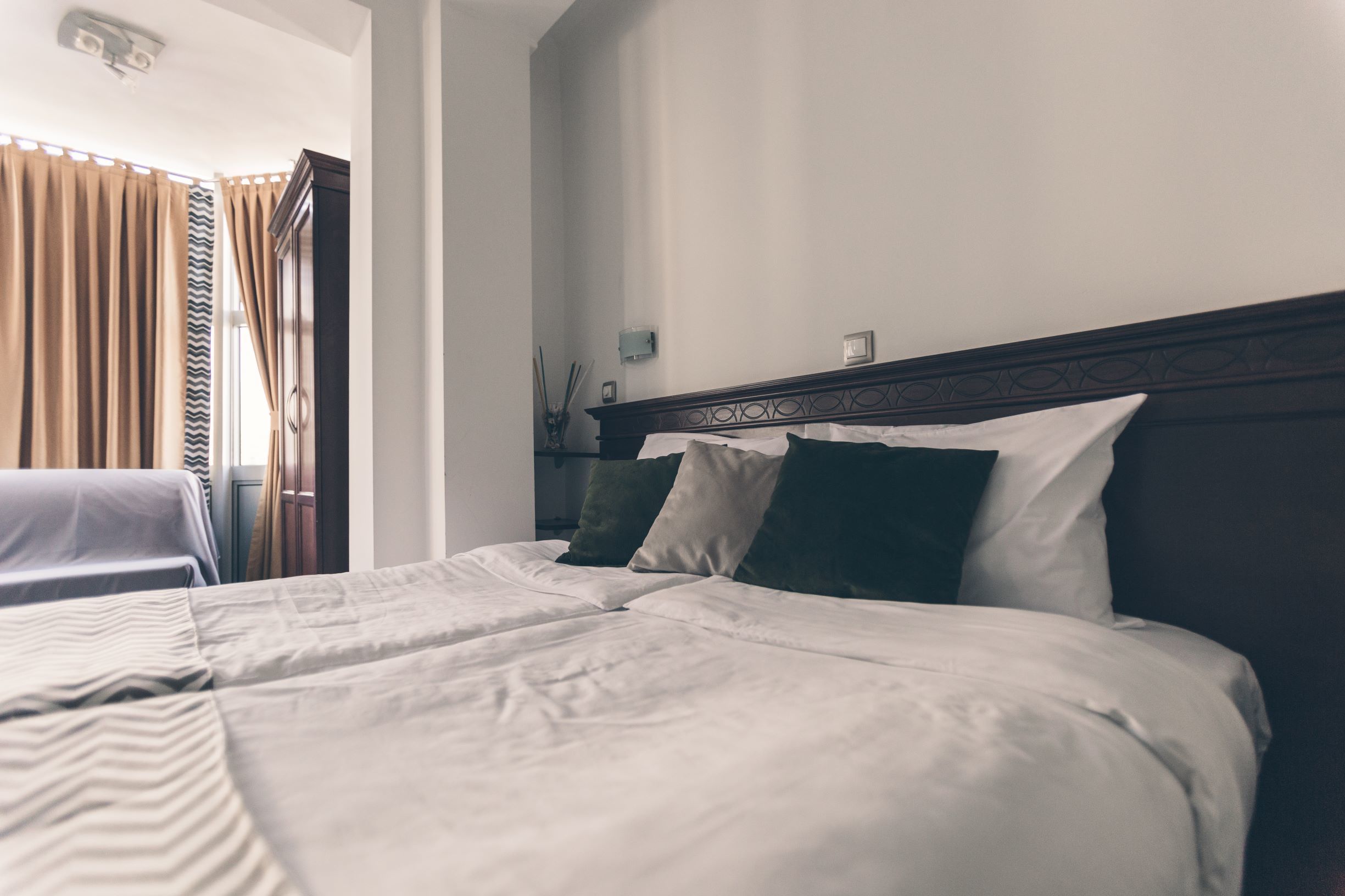A hotel room with a large bed, a nightstand, and a window with curtains.