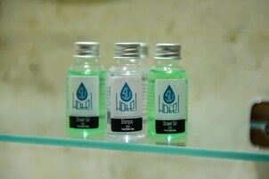 Tres botellas de gel de ducha y champú 3D Hotel sobre un estante de vidrio.