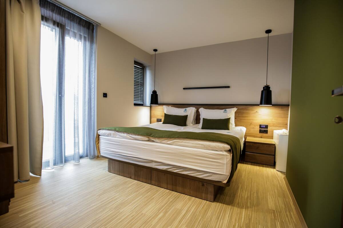 A modern bedroom with a large bed, wooden headboard, bedside tables, and a nightstand.