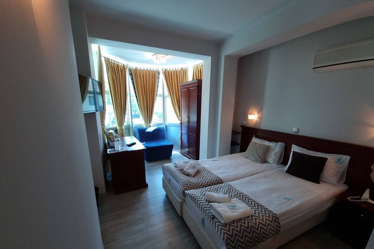 A hotel room with two beds, a desk, a chair, and a sofa.