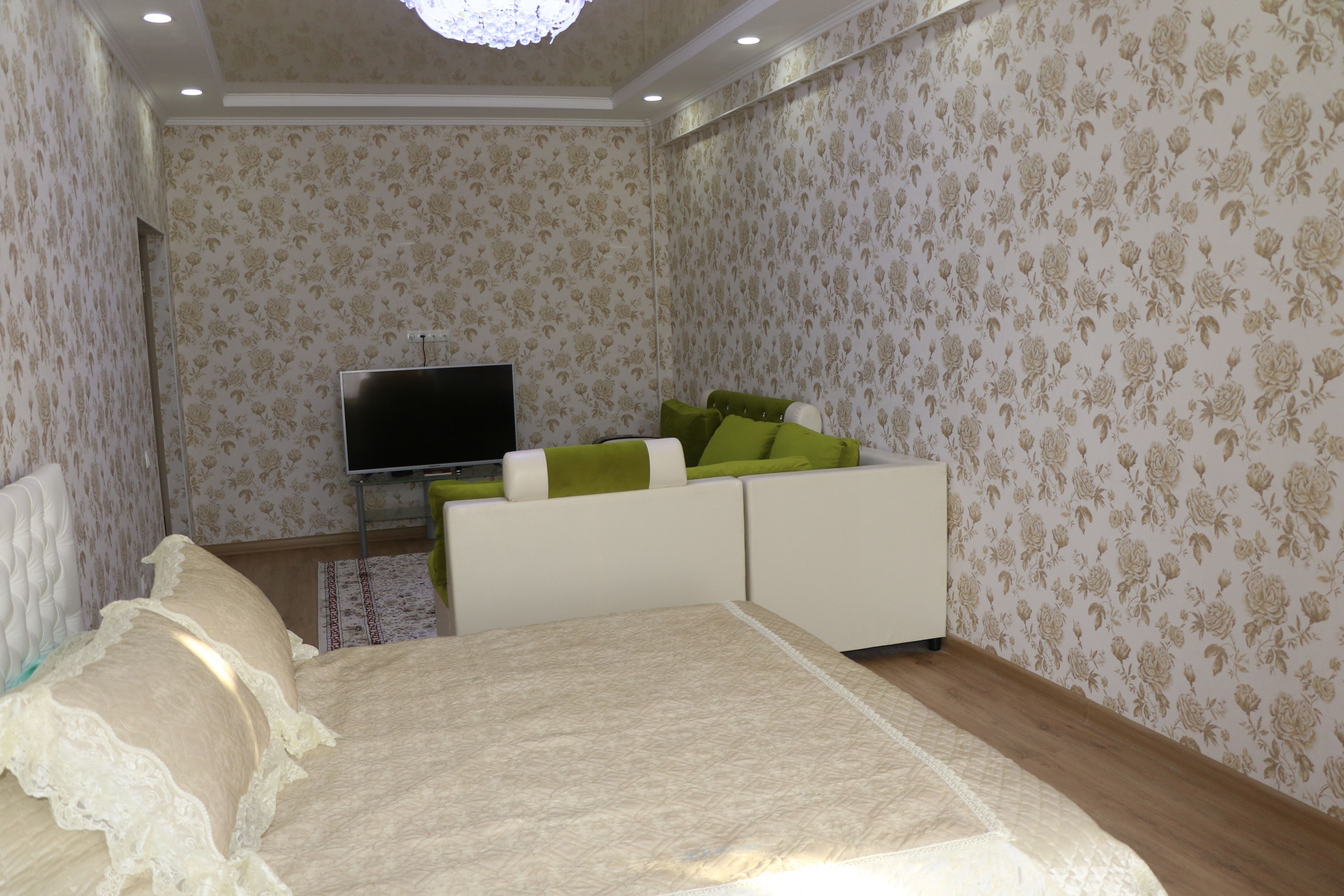 A bedroom with a bed, a TV, and a sofa with green cushions.
