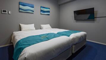 A hotel room with a bed, two wall-mounted TVs, and a blue carpet.