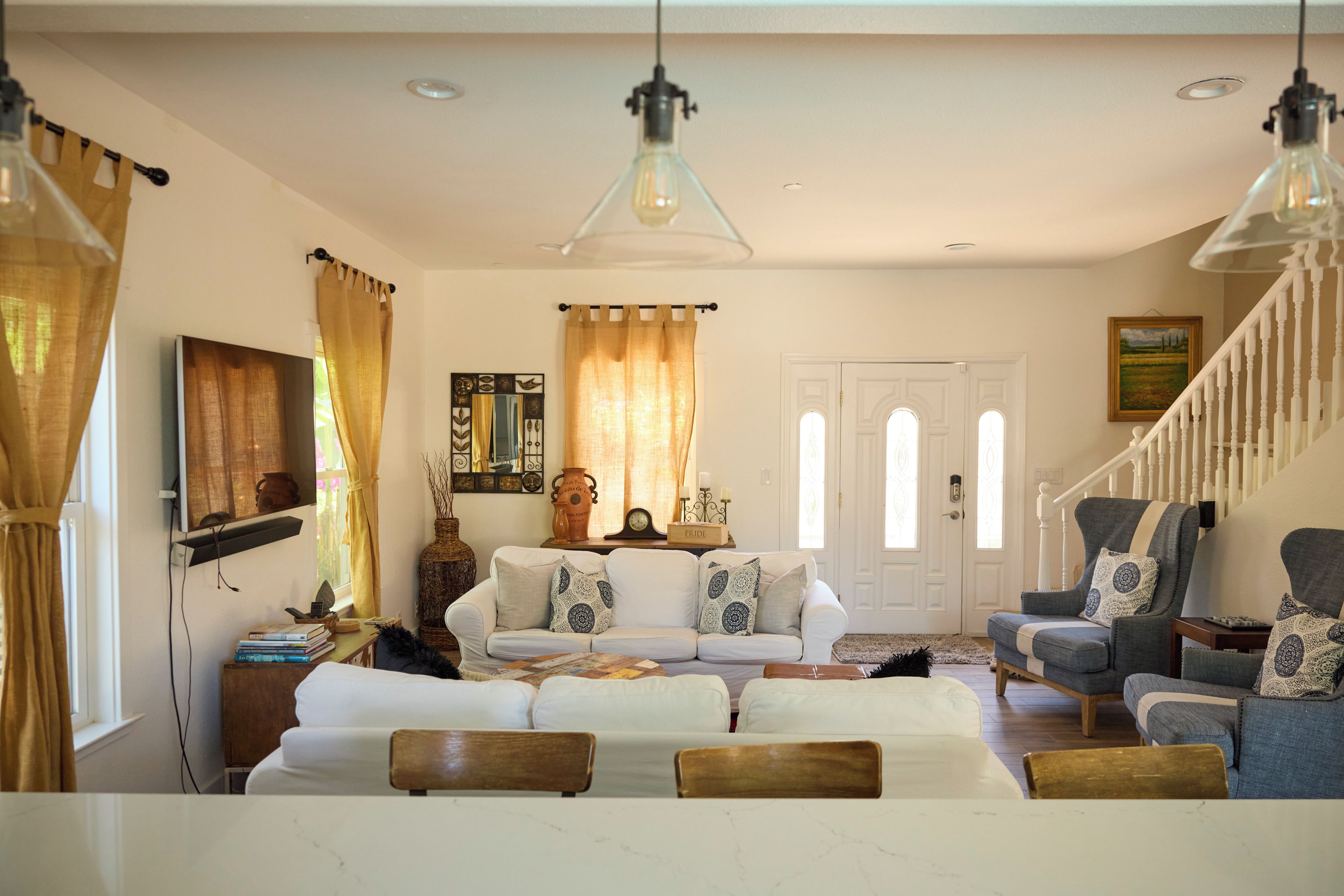 A living room with a white sofa, a blue armchair, a wooden coffee table, and a staircase.