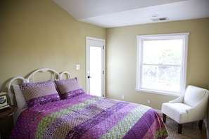 A bedroom with a bed, a chair, a window, and a door.