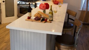 Une cuisine dotée d’un îlot central, d’un four à micro-ondes, d’une cuisinière et d’un coin repas avec une chaise et une table.