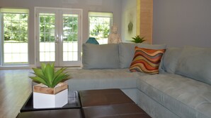 A modern living room with a sectional sofa, a coffee table, and a Buddha statue. - Beautiful 2/2 Apartment in Lake Conroe • Sleeps 6 (Montgomery)