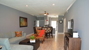 A living room with a sofa, armchair, coffee table, and a TV stand. - Beautiful 2/2 Apartment in Lake Conroe • Sleeps 6 (Montgomery)