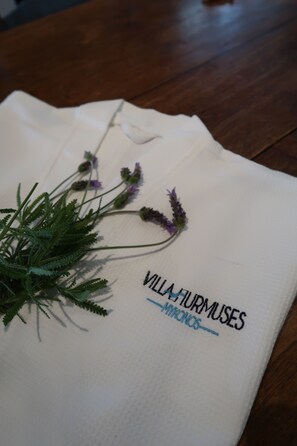 A white cloth with text and a plant on a wooden surface. - Villa Hurmuses (Mykonos)
