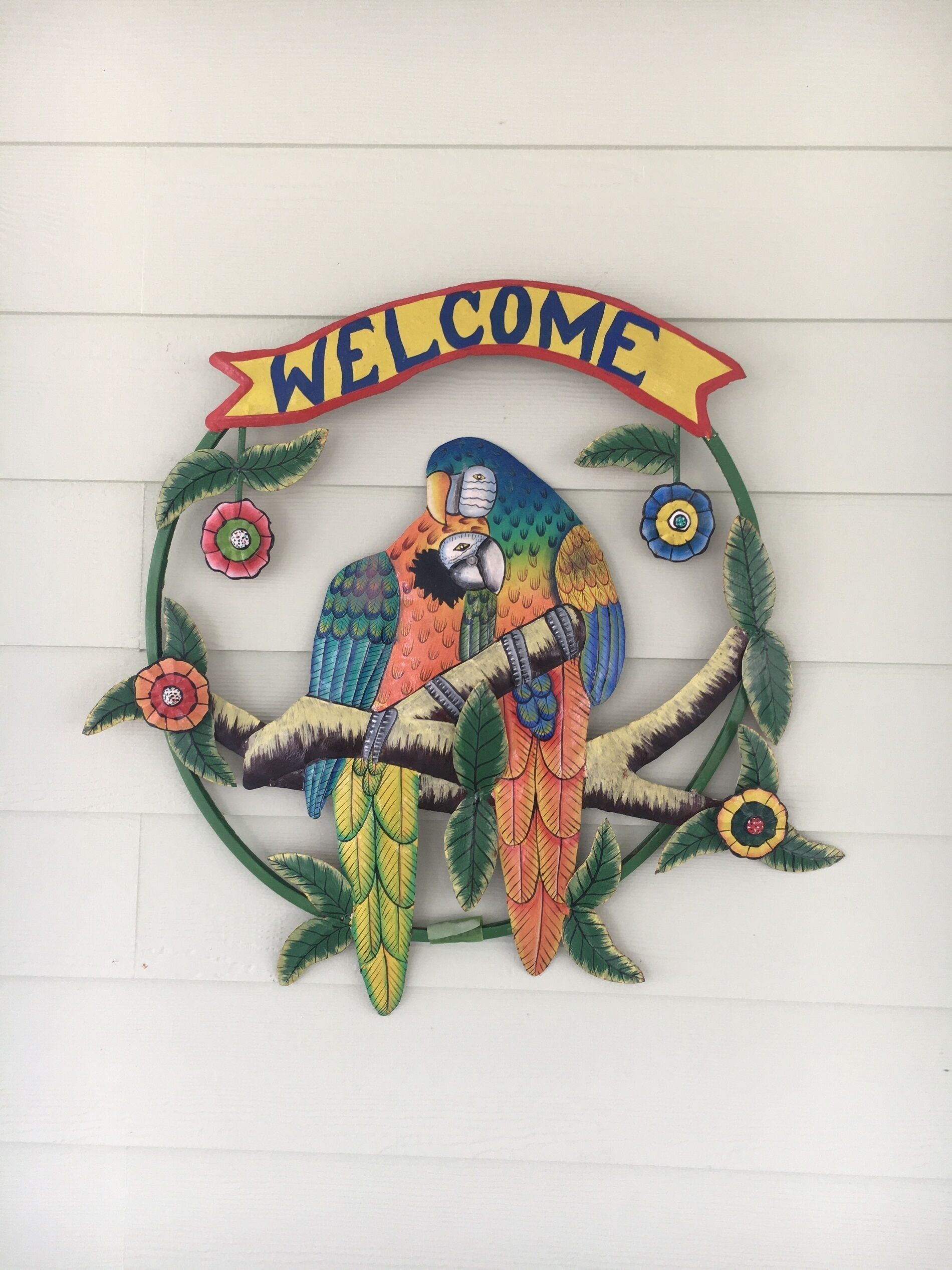 A colorful welcome sign with a parrot and decorative leaves.