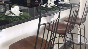 Een moderne keuken met witte kasten, een zwart aanrecht en een centraal eiland met barstoelen.