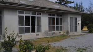 Un edificio de dos pisos con ventanas amplias y techo de tejas.