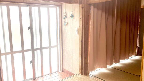 Una habitación con puerta de vidrio corredera, paredes de madera y suelo de tatami.