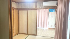 Una habitación con puerta corredera, suelo de tatami y techo de madera.