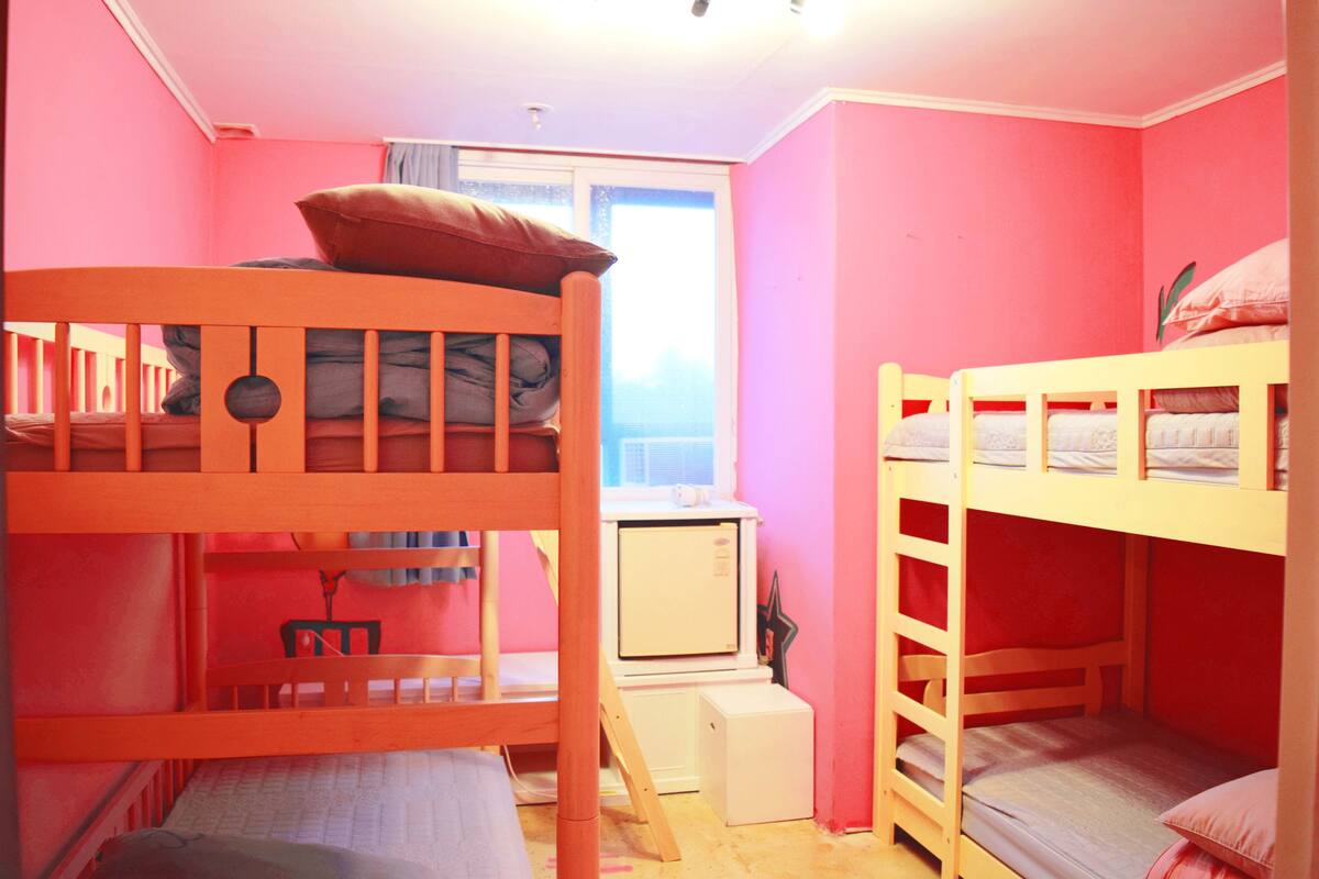 A room with bunk beds, a desk, and a window.