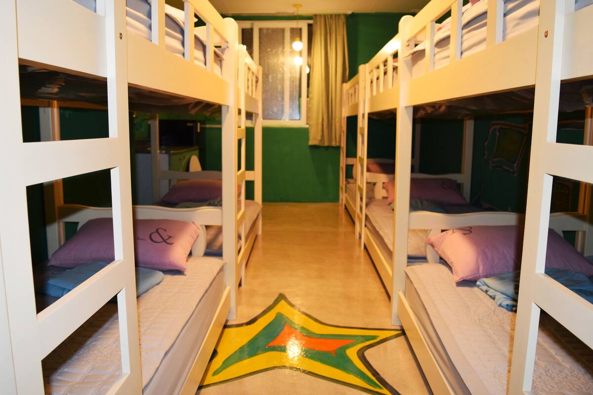 A bunk bed room with a star-patterned floor, green walls, and a window with curtains.