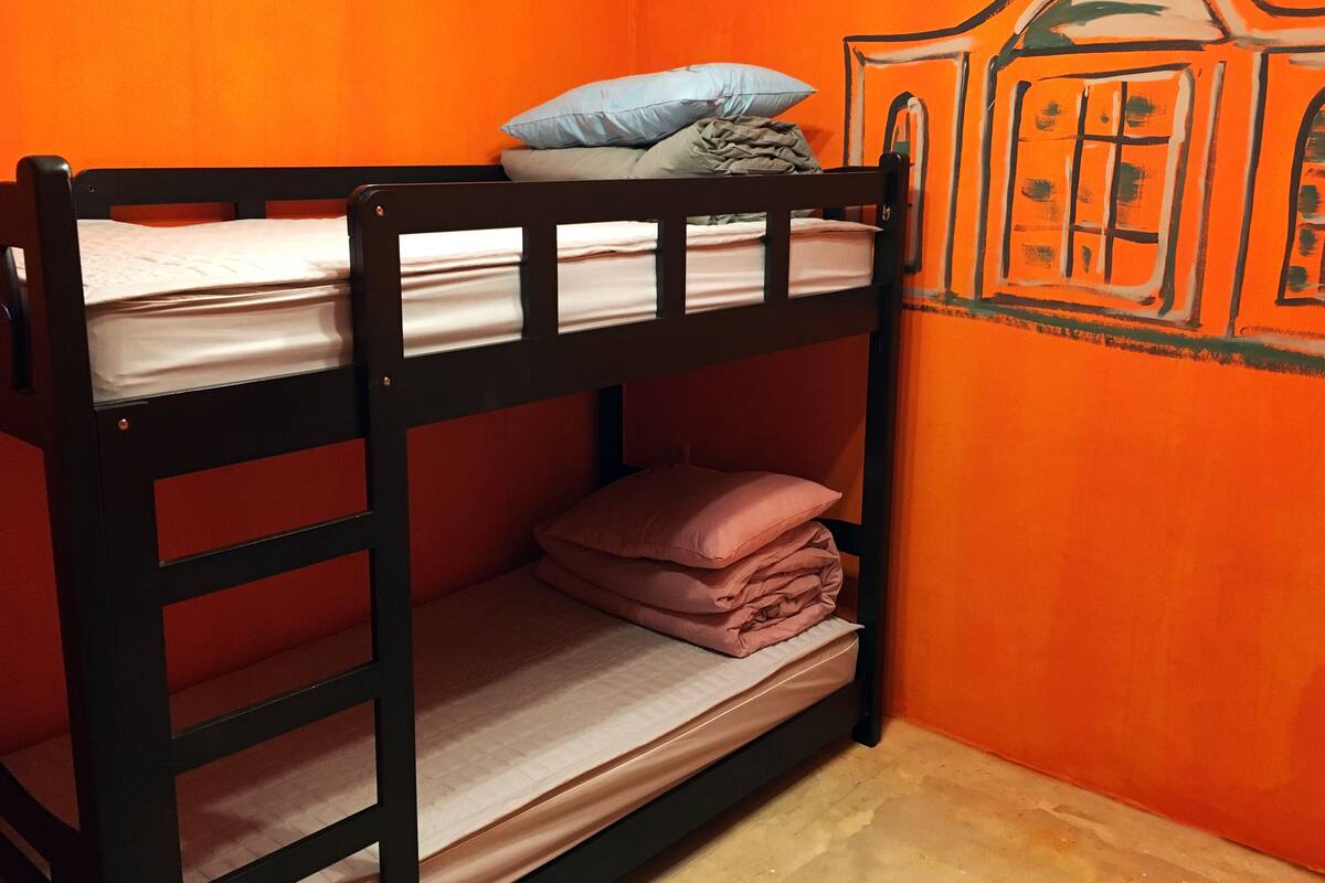 A bunk bed with a pillow and folded blankets.