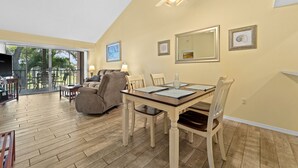 A dining area with a wooden table and chairs, a ceiling fan, and a large window overlooking a patio. - 2/2 Vaulted Ceiling 10 Min to beach on golf course (Venice)