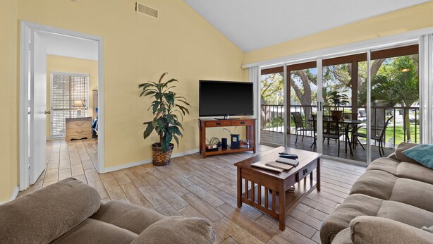 A living room with a sofa, a coffee table, a TV, and a plant. - 2/2 Vaulted Ceiling 10 Min to beach on golf course (Venice)