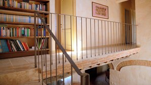 Una escala amb barana metàl·lica que condueix a una plataforma, envoltada d'estanteries plenes de llibres.