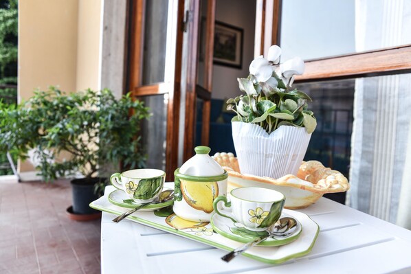 A table set with a tea set, a vase with flowers, and a fruit bowl.