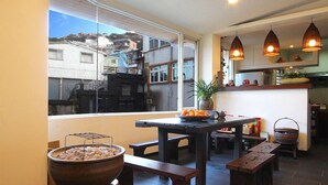A spacious kitchen with a large window, a wooden table, and a grill. - Chien Ching B&B (New Taipei City)