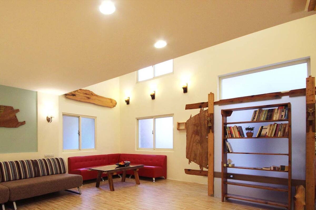 Uma sala de estar espaçosa com um sofá vermelho, um sofá listrado e uma estante de madeira.