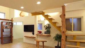 A spacious living area with a wooden staircase, a flat-screen TV, and a bookshelf. - Chien Ching B&B (New Taipei City)