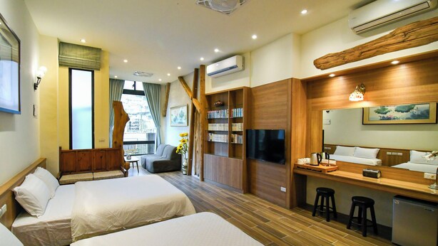 A hotel room with two beds, a small seating area, a kitchenette, and a large window. - Chien Ching B&B (New Taipei City)