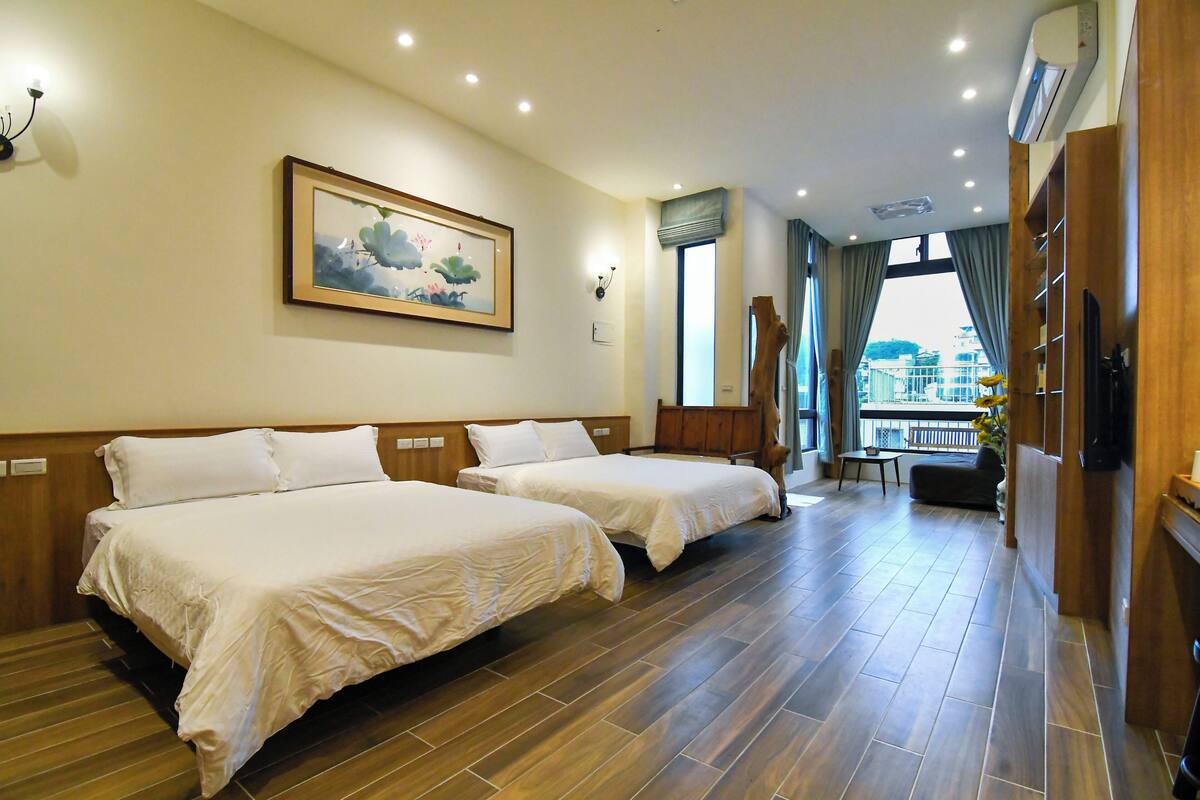 Quarto de hotel com duas camas, um quadro na parede, uma televisão e vista para a cidade pela janela.