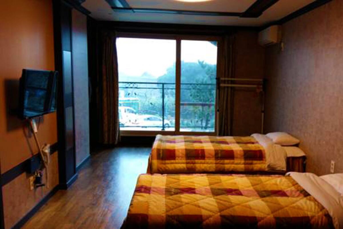 Een hotelkamer met twee bedden, een televisie, een raam met uitzicht en een balkon.