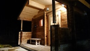 A wooden cabin with a porch, a small table, and a door.