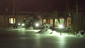 A snow-covered outdoor area with illuminated pathways and a building with large windows in the background.