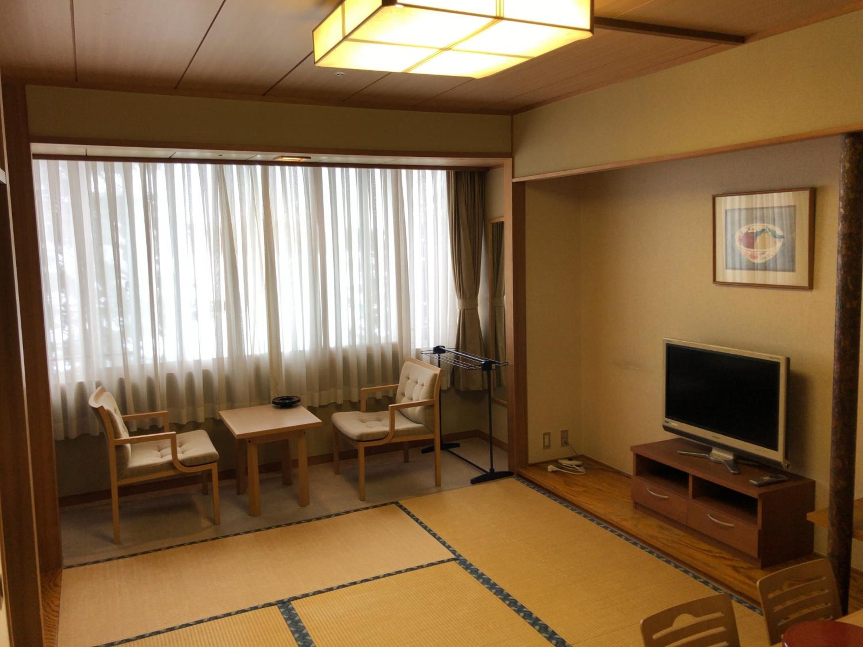 A traditional Japanese room with tatami flooring, a television, and a futon bed.
